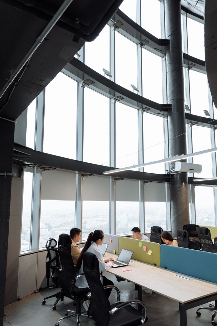 services-02 Spacious contemporary office space with employees working on laptops in a high-rise building.