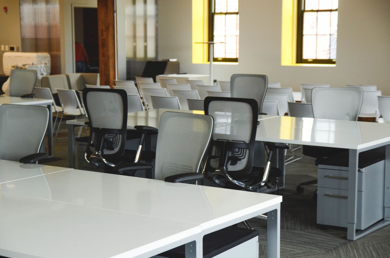 about-01 Spacious open office workspace with desks, chairs, and natural lighting.